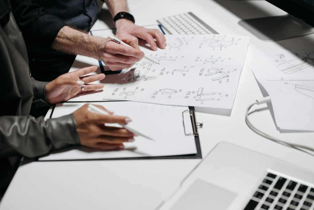 Team members analyzing technical schematics on office workspace. Ideal for business and engineering concepts.
